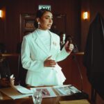 Pewna siebie prawniczka w białym garniturze przemawia w eleganckiej sali sądowej