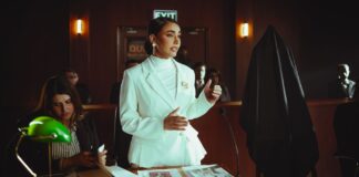 Pewna siebie prawniczka w białym garniturze przemawia w eleganckiej sali sądowej