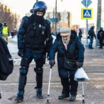 Policjant pomagający starszej kobiecie bezpiecznie przejść przez ulicę