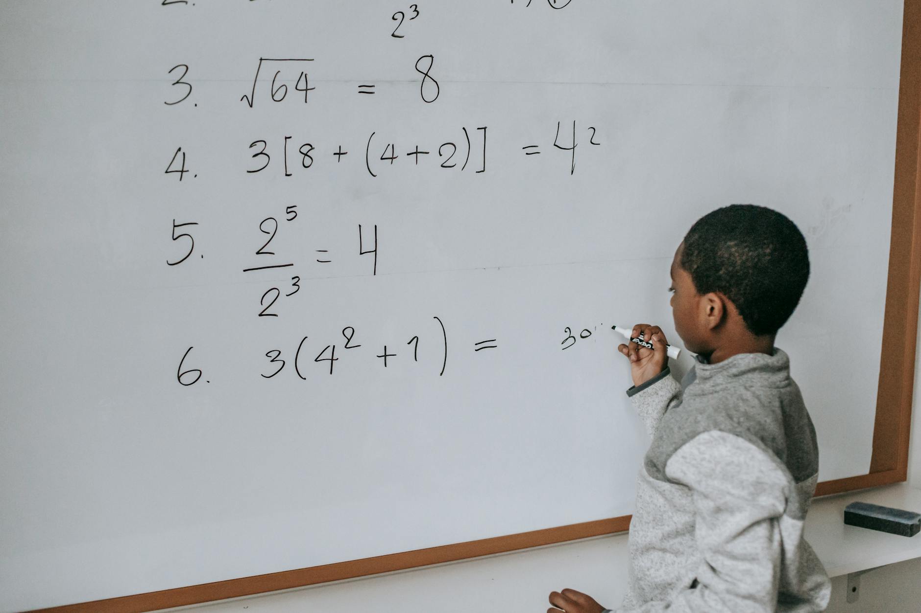 Uczeń przy tablicy rozwiązuje zadania matematyczne w szkolnej klasie
