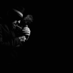Gangster jako antybohater naszych czasów: psychologia fascynacji mafią Czarno-biały portret mężczyzny odpalającego papierosa w mroku