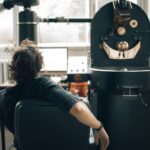 Mężczyzna obserwuje proces palenia kawy na nowoczesnej linii produkcyjnej
