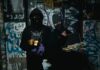 Dwóch zamaskowanych przestępców z bronią w zaułku pokrytym graffiti