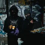 Dwóch zamaskowanych przestępców z bronią w zaułku pokrytym graffiti