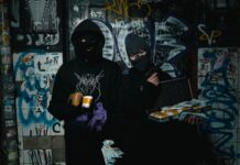 Dwóch zamaskowanych przestępców z bronią w zaułku pokrytym graffiti