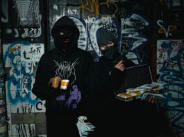 Dwóch zamaskowanych przestępców z bronią w zaułku pokrytym graffiti