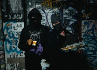 Dwóch zamaskowanych przestępców z bronią w zaułku pokrytym graffiti