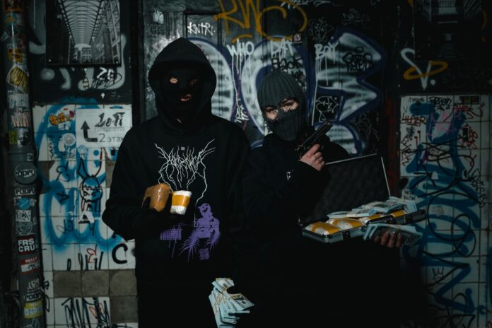 Dwóch zamaskowanych przestępców z bronią w zaułku pokrytym graffiti