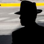 Zacieniona sylwetka mężczyzny w kapeluszu na miejskiej ulicy