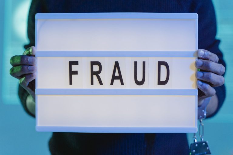Dłonie trzymające kartkę z napisem fraud w niebieskim świetle